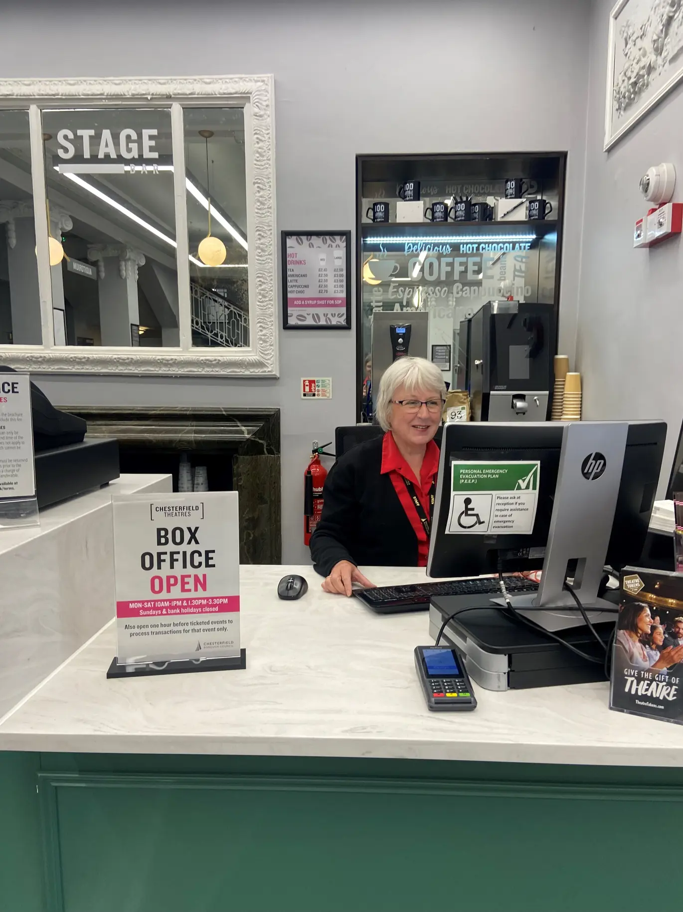 A staff member sits at the box office facing a computer screen.